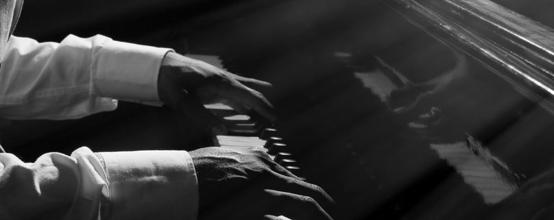Hands playing piano in darkness